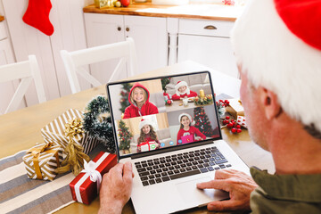 Wall Mural - Senior caucasian man having christmas video call with diverse children