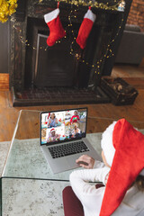 Sticker - Caucasian woman with santa hat having christmas laptop video call with happy diverse friends