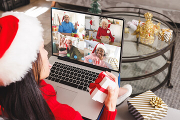 Canvas Print - Caucasian woman with santa hat having video call with happy diverse friends