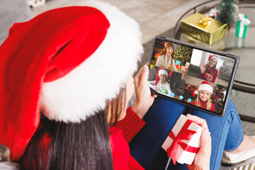 Wall Mural - Caucasian woman with santa hat having video call with happy caucasian friends