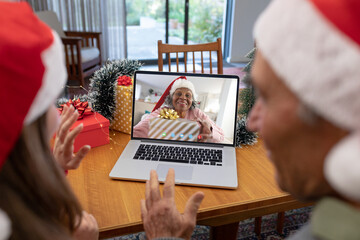 Poster - Caucasian father and daughter with santa hats having video call with happy african american woman