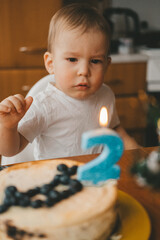 portrait of a two-year-old child in front of a birthday cake with candles with the number two