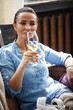 © Maksim Toome - Leisure time concept. Happy beautiful woman drinks white wine from glass sitting on a couch indoors. Female spending her free day and relaxing at home alone.