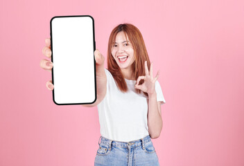 Asian young woman showing smart phone with blank screen , white screen for Mobile App Advertising isolated on pink background ,Cell phone display Mock Up Image.