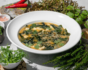 Poster - Japanese miso soup in  white restaurant plate on light stone table, copy space. Asian miso soup with tofu.
