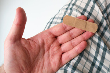 male hand with a medical adhesive plaster close-up. adhesive plaster on damaged skin. first aid for 