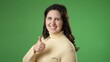 © Robert Peak - Smiling happy satisfied young woman 20s turn around to camera showing thumbs up like gesture isolated on green screen background studio portrait. People lifestyle concept