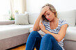 © Jelena Stanojkovic - Anxious worried woman sitting on couch at home. Frustrated confused female feels unhappy, problems in personal life, quarrel breakup with boyfriend and unexpected pregnancy concept.