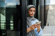 © Drobot Dean - Muslim woman using mobile phone while standing outdoors