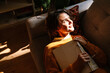 © Drobot Dean - Brunette young woman reading book while resting on couch