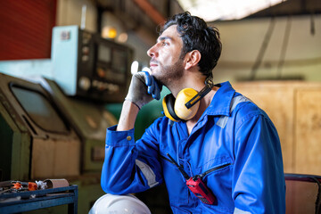 Mechanical man in uniform on break time sitting look over window heavy machinery in background