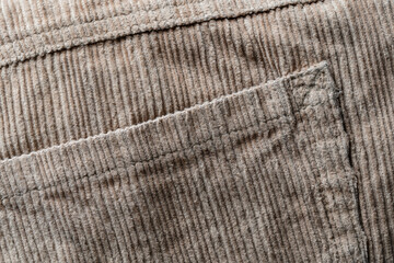 Wall Mural - Texture backdrop of beige colored corduroy fabric cloth with pocket . Corduroy retro fabric background or texture. Closeup view