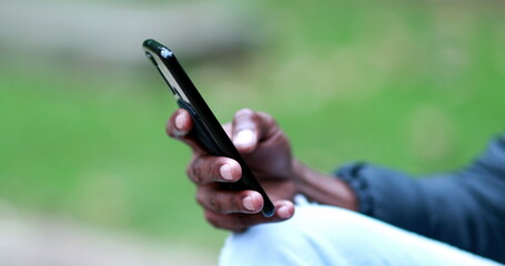 Close-up hand using smartphone, african black person checking cellphone outdoors