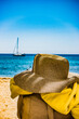  Un chapeau en paille sur une plage du var en France en plein été, on devine un voilier au loin au mouillage.