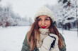 © maryviolet - Close up portrait of happy young woman in snowy winter park wearing warm knitted clothes and red festive lipstick.
