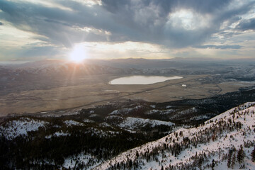 Wall Mural - Aerial view landscape with snow covered mountains at sunrise with a dramatic sky.