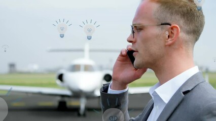 Canvas Print - Animation of lightbulb icons over caucasian businessman at airport