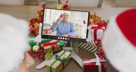 Sticker - Diverse couple with santa hats having tablet video call with biracial man