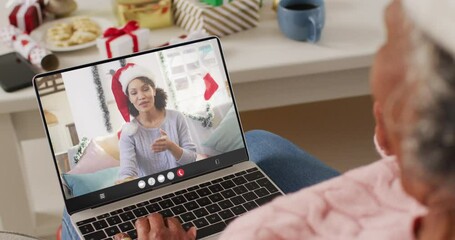 Canvas Print - Animation of african american woman in santa hat on laptop video call with woman at christmas