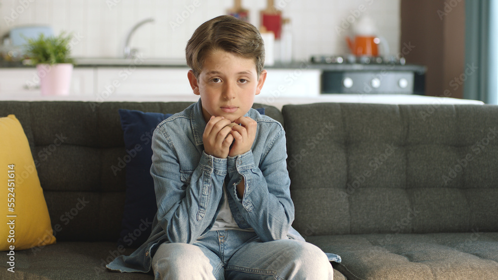 Portrait of a sad, anxious child sitting alone at home, representing childhood anxiety symptoms