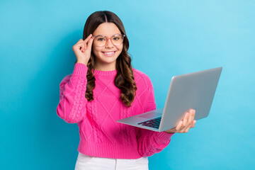 Sticker - Photo of cheerful smart schoolgirl wear eyeglasses knitted pink jumper touch specs hold laptop youtube user isolated on blue color background