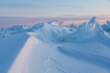 Wall Mural - Winter arctic landscape. Cold frosty winter weather. Harsh polar climate. Ice hummocks on the frozen sea in the Arctic. View of snow and ice at sunset. Sastrugi. Wind sculpted patterns on snow surface