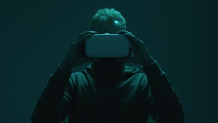 Astonished guy holding augmented reality tool. Portrait of a man wearing VR goggles in dark neon-colored room. High quality 4k footage