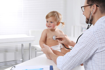 Canvas Print - Pediatrician examining baby with stethoscope in clinic