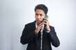 © AriaSandi - Young Asian Man is confused and shocked when calling in the phone. Indonesian man wearing a black suit.