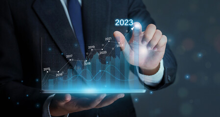 Wall Mural - Businessman holding tablet with draws increase arrow graph corporate future growth year 2022 to 2023.Planning,opportunity, challenge and business strategy. Development to success and growth business.