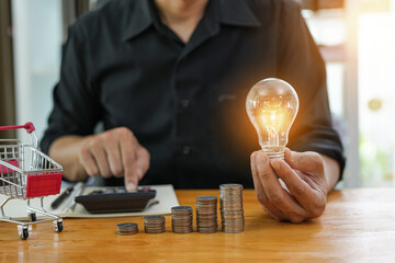 Business man holding light bulb on the Green background nature and writing on note book it for financial