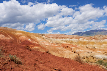 The red mountains of Altai on the background of the blue sky with clouds. Tourist places in the Altai Mountains for hiking tours. 