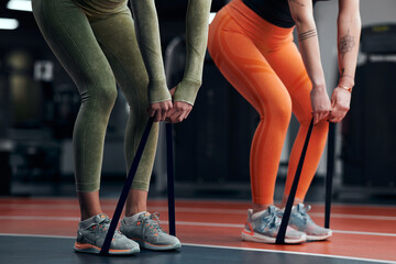 Sporty women in gym exercising with elastic resistance rubber band.