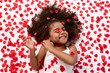 © Lisa Tichané - Funny young girl with afro hair laughing on bed surrounded by heart shaped confetti
