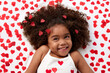© Lisa Tichané - Happy young girl with afro hair giggling on bed surrounded by heart shaped confetti