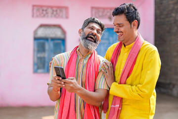 Two indian farmer using smartphone at home