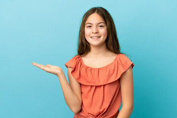 Wall Mural - Little caucasian girl isolated on blue background holding copyspace imaginary on the palm to insert an ad