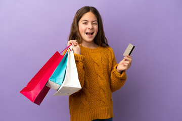 Canvas Print - Little caucasian girl isolated on purple background holding shopping bags and a credit card