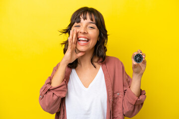 Young latin woman holding compass isolated on yellow background shouting with mouth wide open