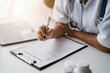 © NINENII - Doctor working to write a patient report in the clinic.