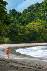 Wall Mural - A beautiful girl in a pink bikini walks on a tropical beach with palm trees in manuel antonio national park in quepos, Costa Rica; tropical paradise beach in Costa Rica