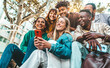 © Davide Angelini - Happy young people using smart mobile phone device outdoors - Multiracial friends watching smartphone on city street - Cheerful students having fun with trendy technology in college campus