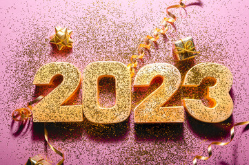 Happy New Year 2023. Golden digits 2023 with glitter and xmas decorations nearby. Holiday Party Decoration or postcard concept with top view and copy space.