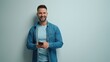 © nyul - Portrait of happy casual man using phone, Young guy standing at white wall, smiling, Isolated on white background, blank copy space.