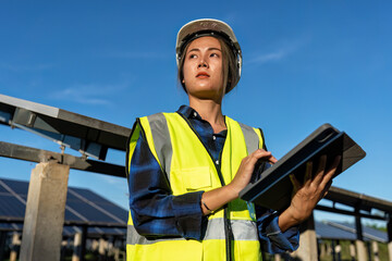 Maintenance engineer at greenery Solar farm at work hold tablet standing portrait to camera