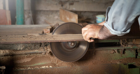 Wall Mural - Carpenter cutting a wooden plank with a carpentry machine.