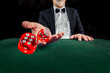 © TSViPhoto - Gambling concept. Close up of male hand throwing dice at casino, gambling club. Сasino chips or Casino tokens, poker cards, gambling man spending time in games of chance