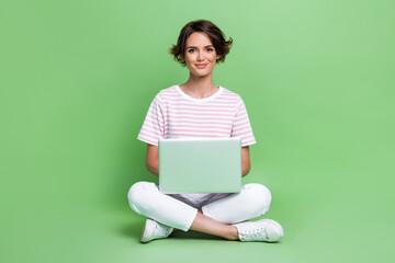 Full length photo of gorgeous young girl coding new software laptop working wear stylish striped garment isolated on green color background