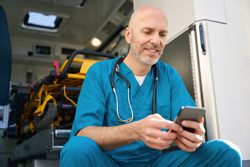 Man sits by open cockpit of an ambulance with smile