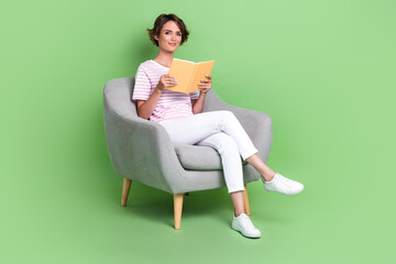 Sticker - Full body photo of nice young girl soft armchair library enjoy read book wear stylish striped clothes isolated on green color background